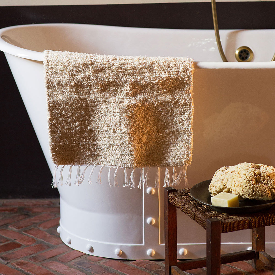 Hand Wove Bath Mat Draped Over Bath Tub